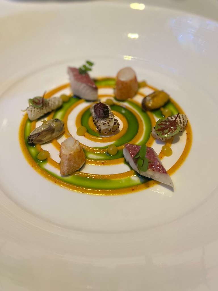 Al Mahara seafood plated in a spiral of green and orange sauces