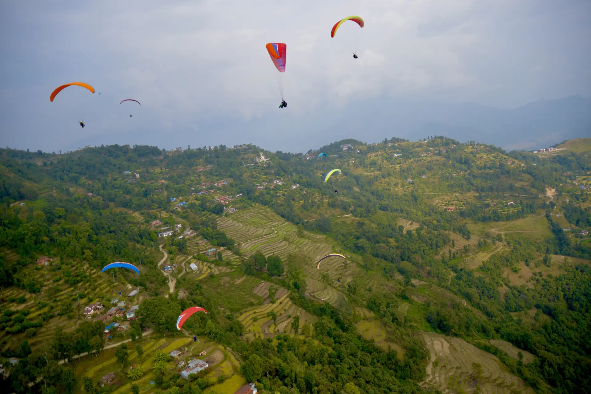 Colorful paragliders drifting over the terraced hills of Pokhara