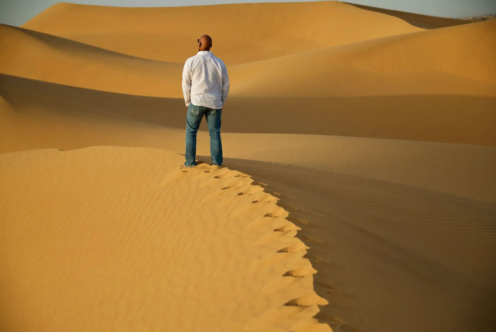 Traveller standing alone on a desert dune at golden hour