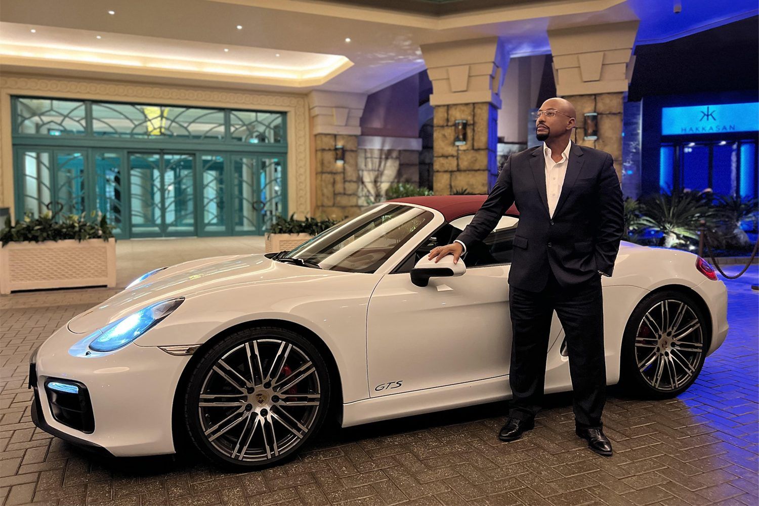 Eddie alongside a luxury Porsche outside a resort